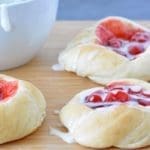 Cherry danishes on a cutting board.