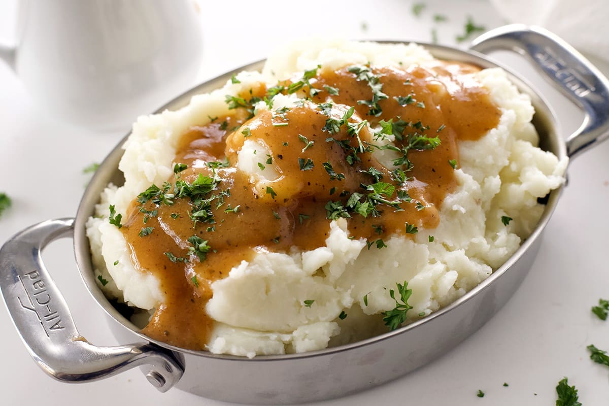 Mashed potatoes in a silver dish with cajun gravy.