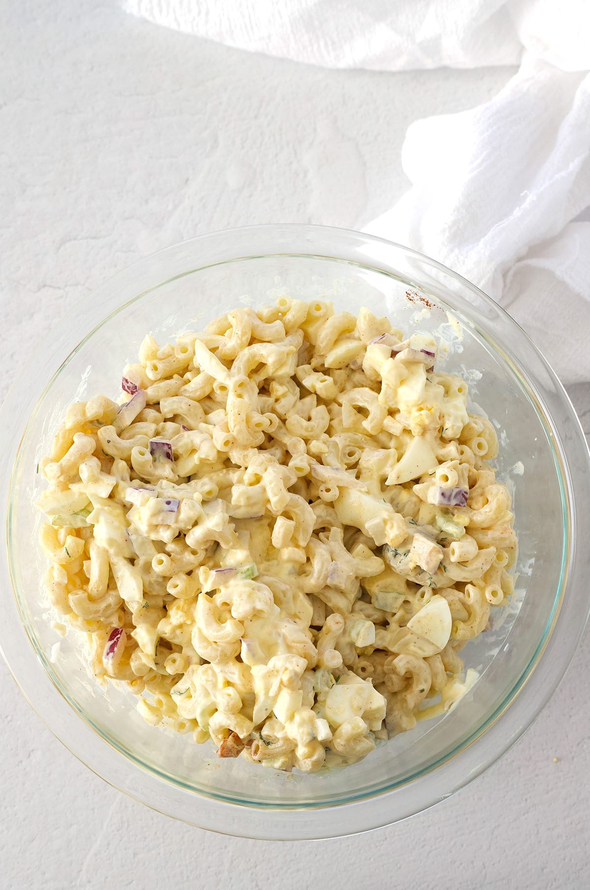 Clear bowl full of pasta salad with deviled eggs.