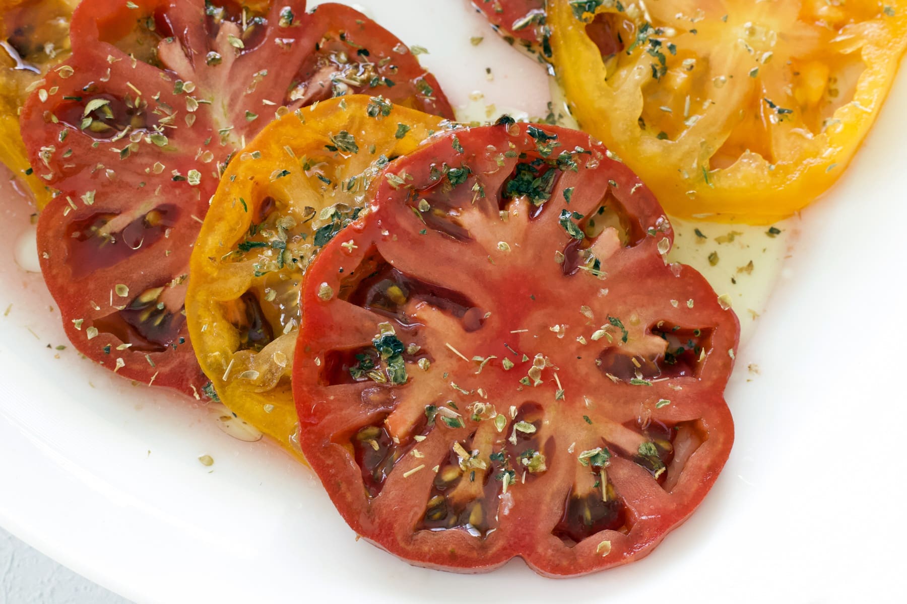 Sliced produce topped with dried herbs.