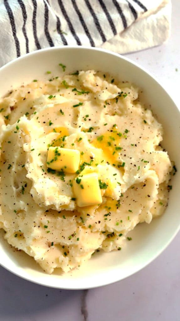 Bowl of mashed potatoes topped with butter.