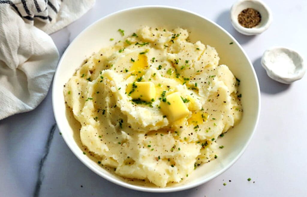 Mashed potatoes topped with butter in a white bowl.
