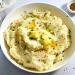 Mashed potatoes topped with butter in a white bowl.