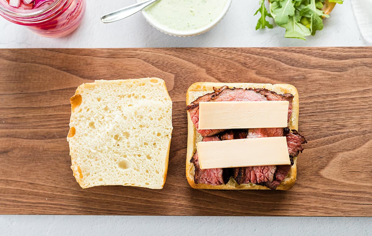 Two slices of bread with meat and cheese on top.