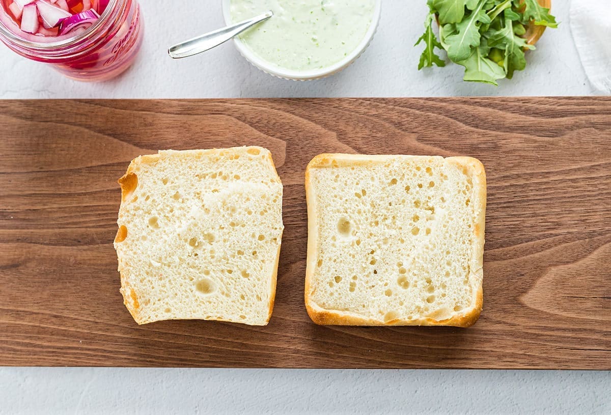 Two slices of ciabatta bread on a cutting board.