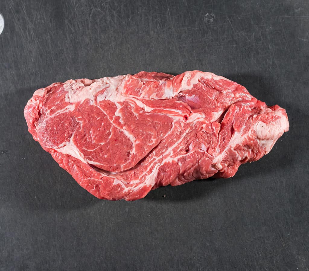 Large chuck roast on a black cutting board.