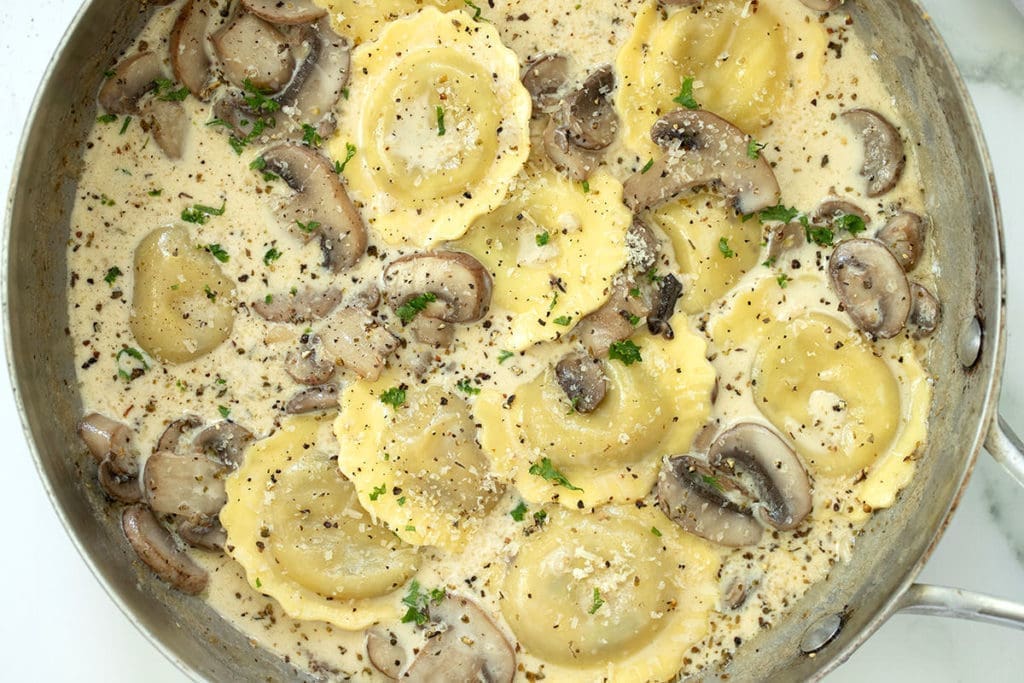 Mushroom ravioli in a silver skillet.