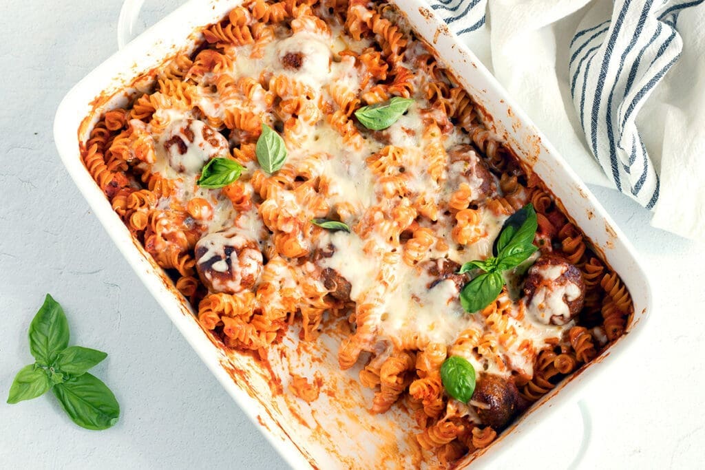 Meatball casserole garnished with basil.