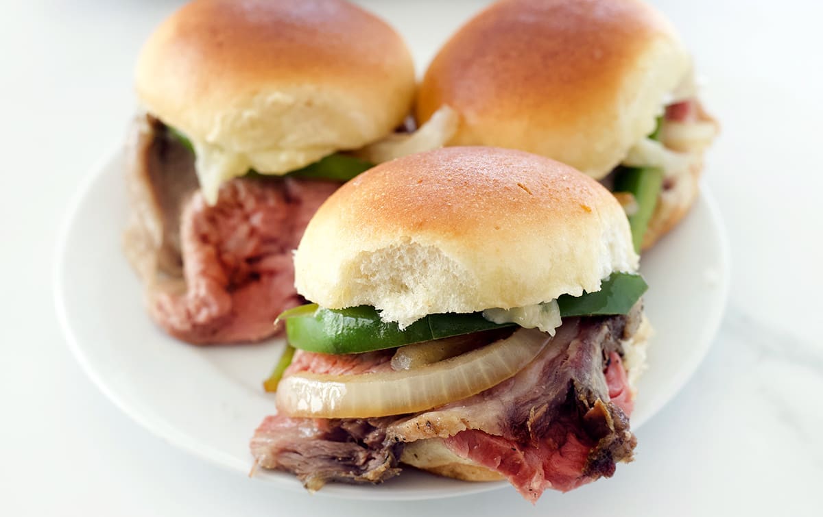 White plate with 3 Philly cheesesteak sliders.