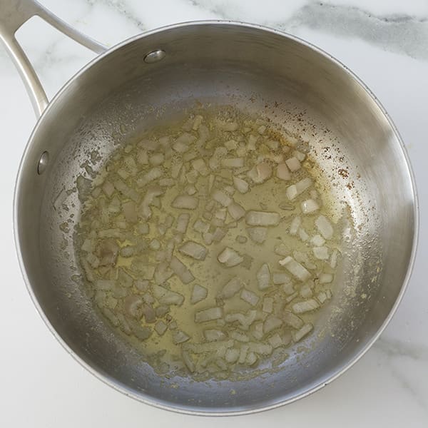 Silver saucepan with butter and shallot.