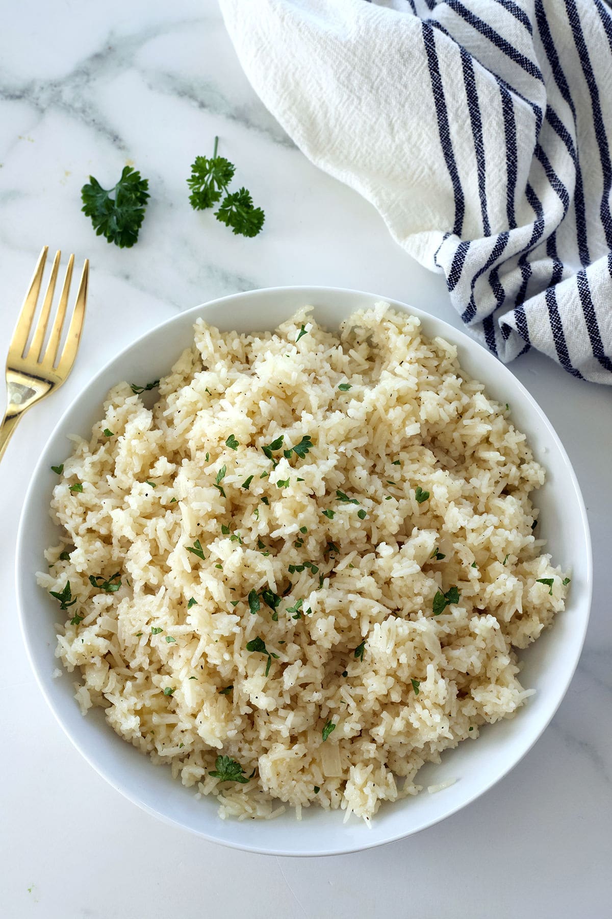 White bowl of cheesy rice with a gold fork.