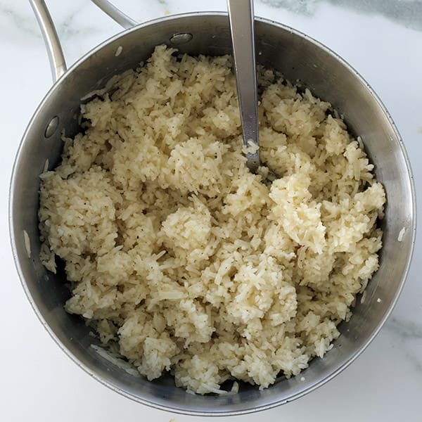 Silver saucepan with rice and fork inside.