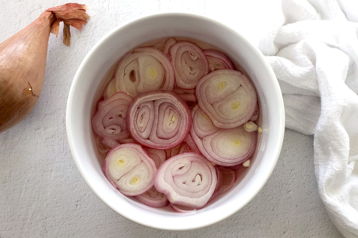 White bowl of pickled shallots.