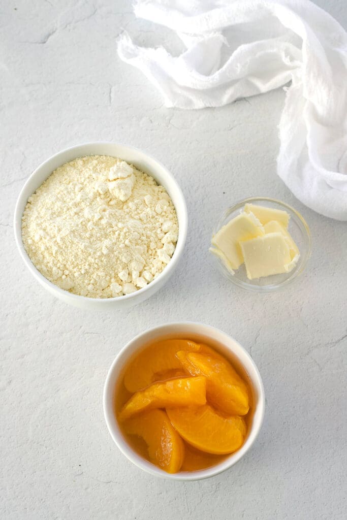 Bowl of peaches, cake mix and butter.