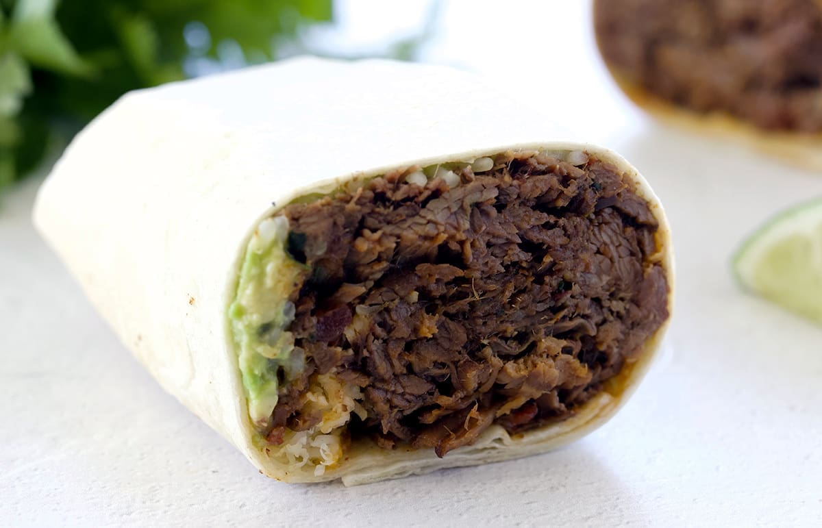 Cut in half shredded beef burrito.