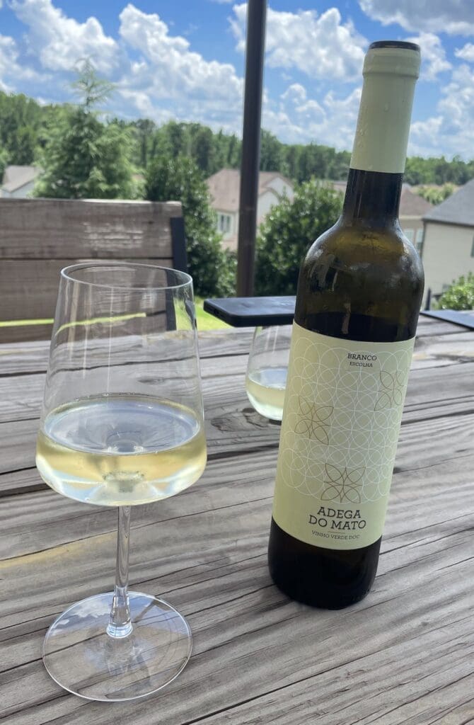 bottle and glass of white wine on outdoor table.